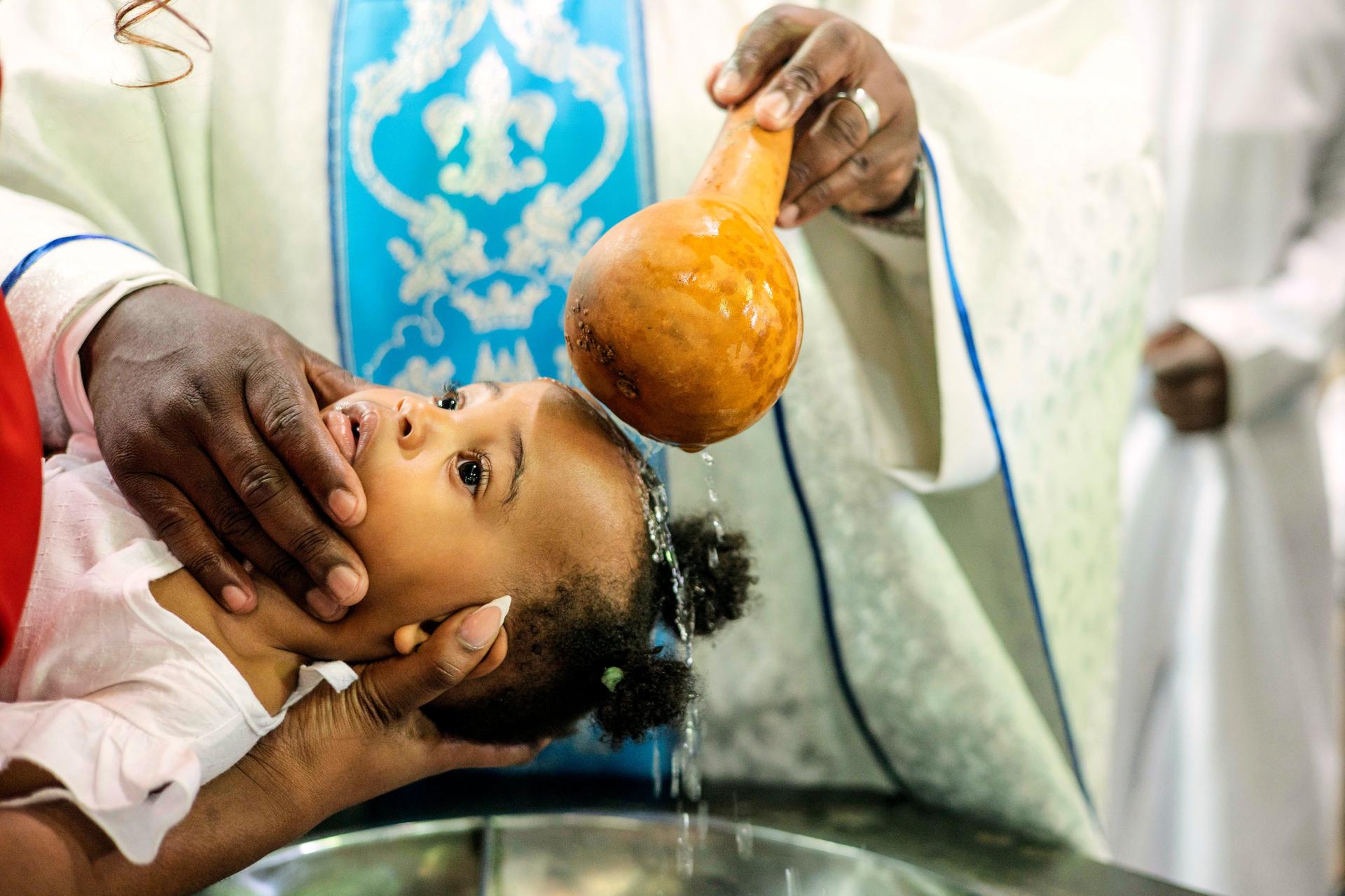 A priest pours water over the head of a child during a baptism ceremony at the Roman Catholic Cathedral in Harare, Zimbabwe, April 5.