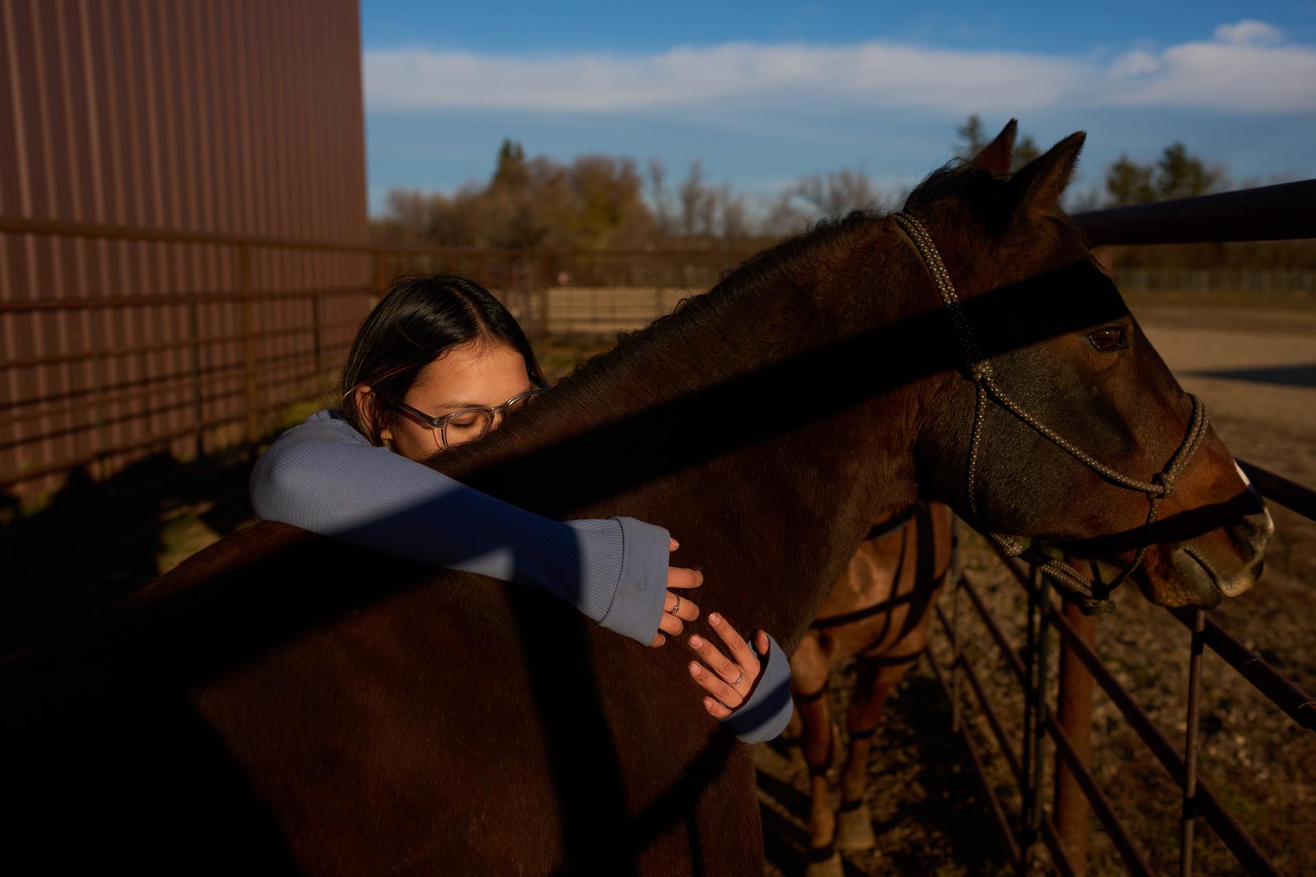 Sydney Diaz-Corral embraces a horse during a class in the Nueta Hidatsa Sahnish College equine studies program in October. (AP Photo/John Locher)
