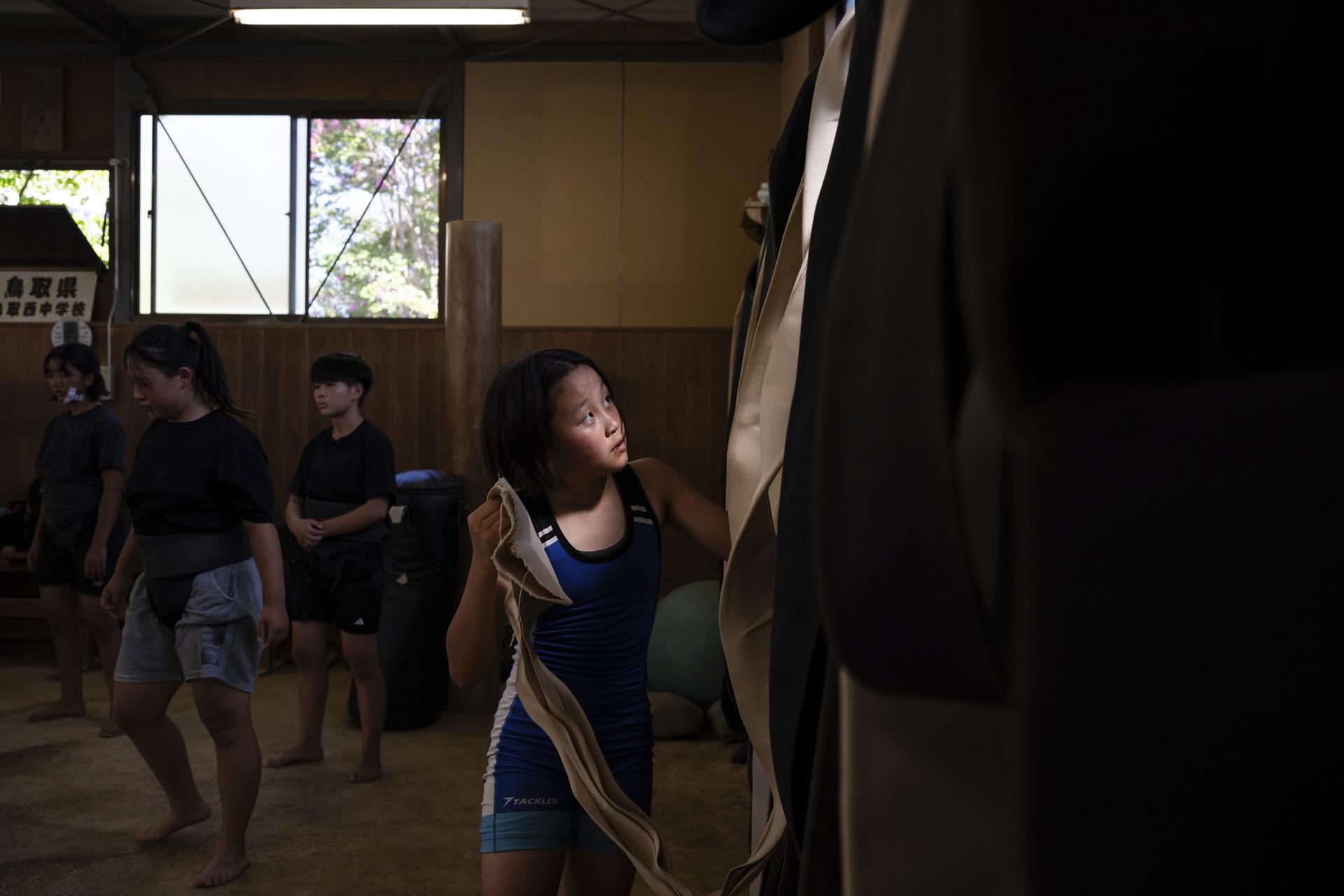 A wrestler picks up a belt prior to a practice session at a sumo camp in Tottori Johoku High School in Tottori, Japan, in July.