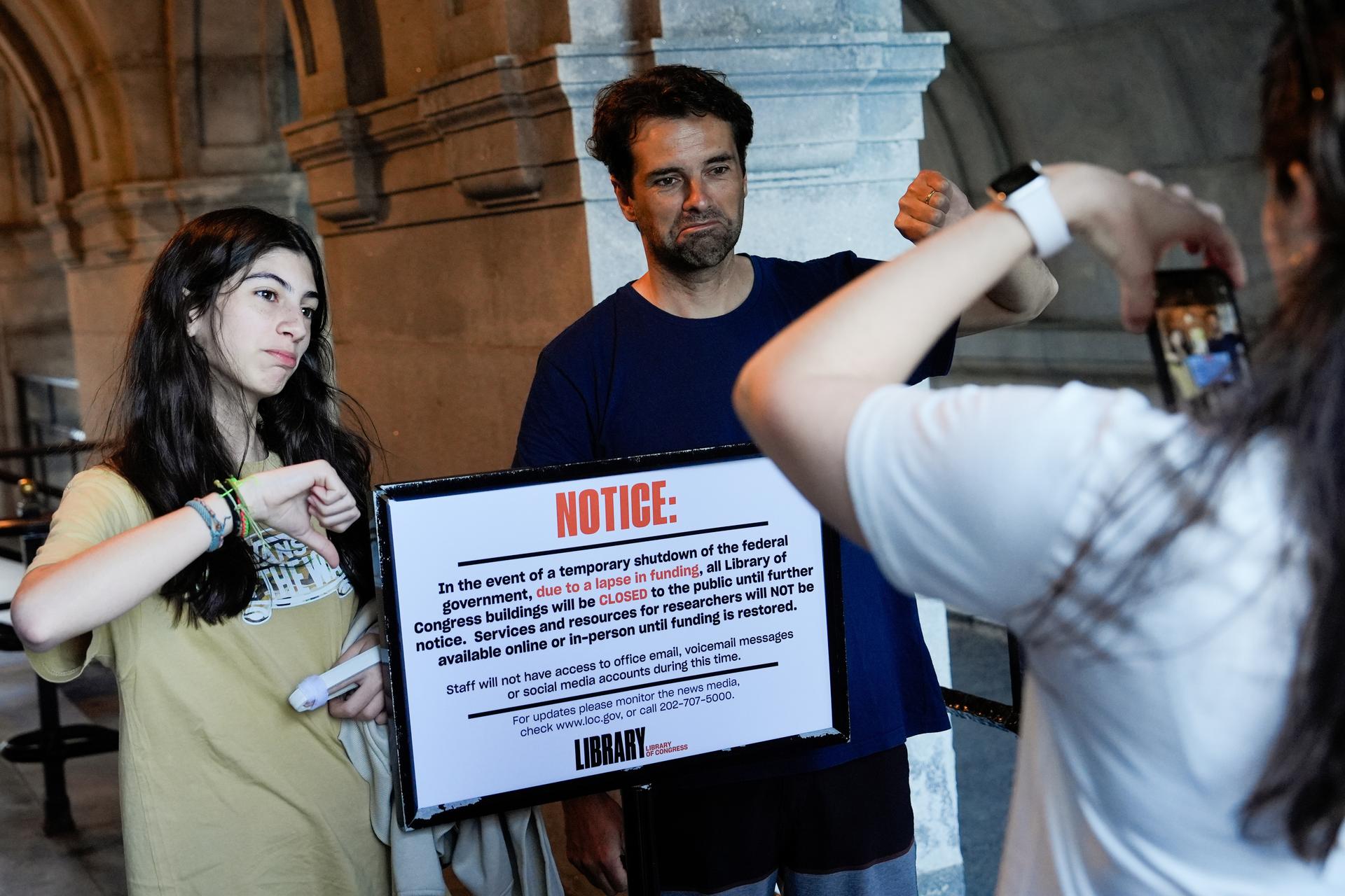 People take photos with a sign announcing that the Library of Congress is closed on Wednesday. (AP Photo/Julia Demaree Nikhinson)