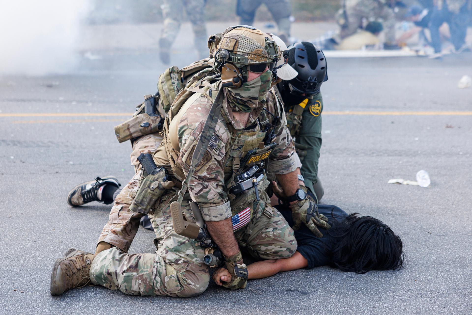 Federal officers hold down a protester in Chicago after protesters learned that U.S. Border Patrol shot a woman Saturday morning on Chicago's Southwest Side.