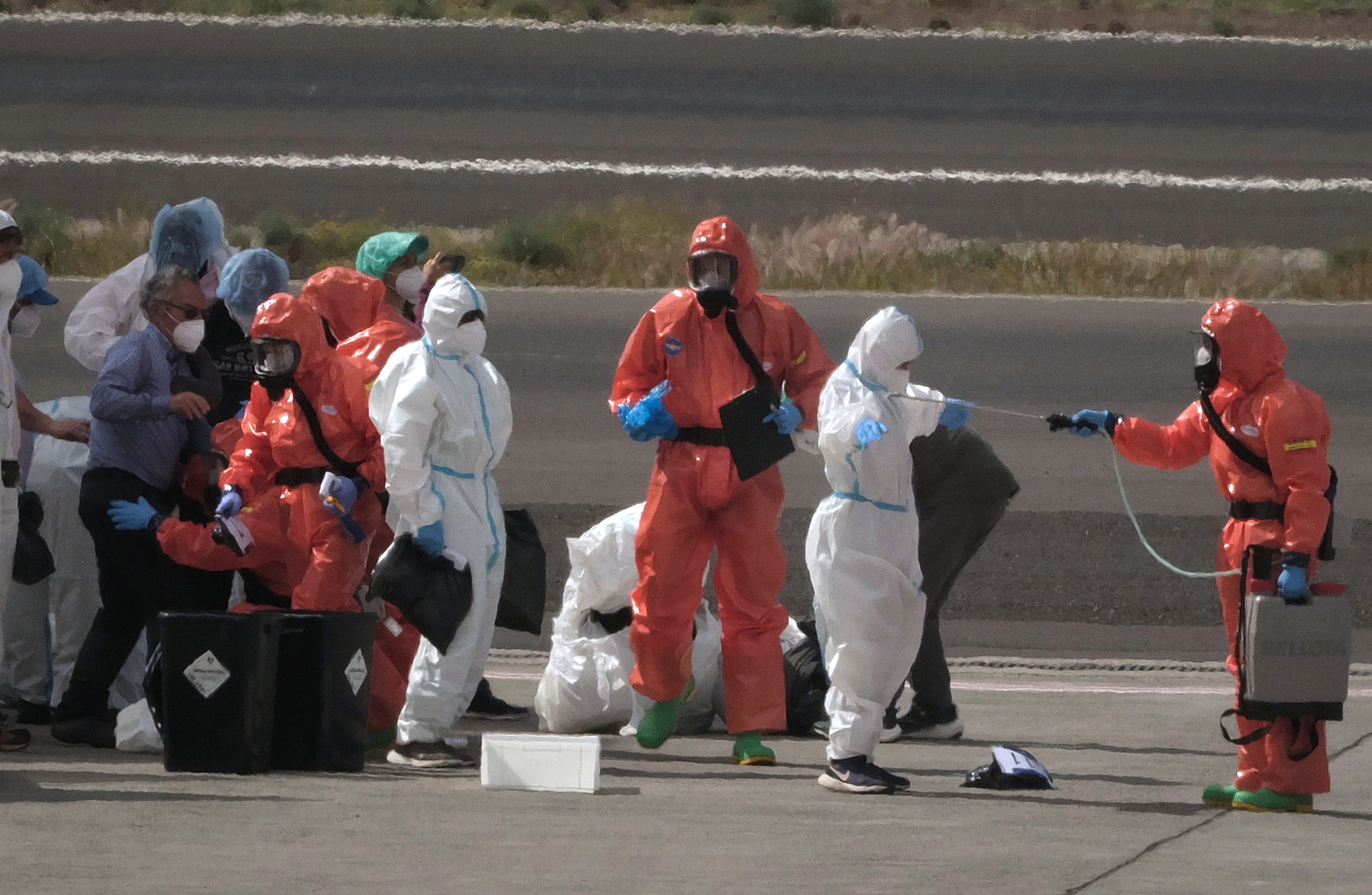 Passengers are sprayed with disinfectant by Spanish government officials before boarding a plane after disembarking from the hantavirus-stricken cruise ship MV Hondius at Tenerife airport in the Canary Islands, Spain on Sunday.