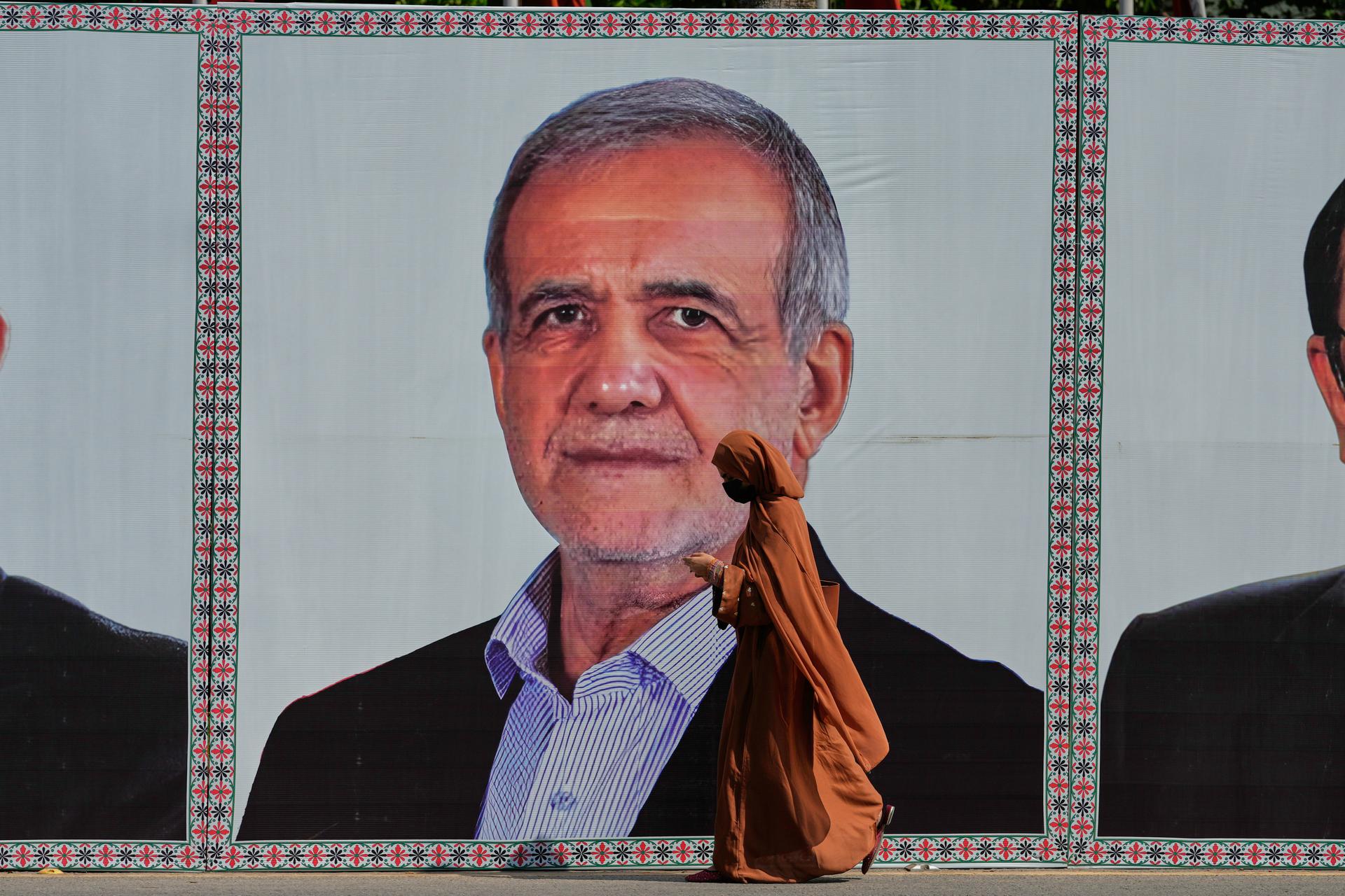 A woman walks past a welcoming billboard featuring Iranian President Masoud Pezeshkian along a roadside in Islamabad, Pakistan, June 23.