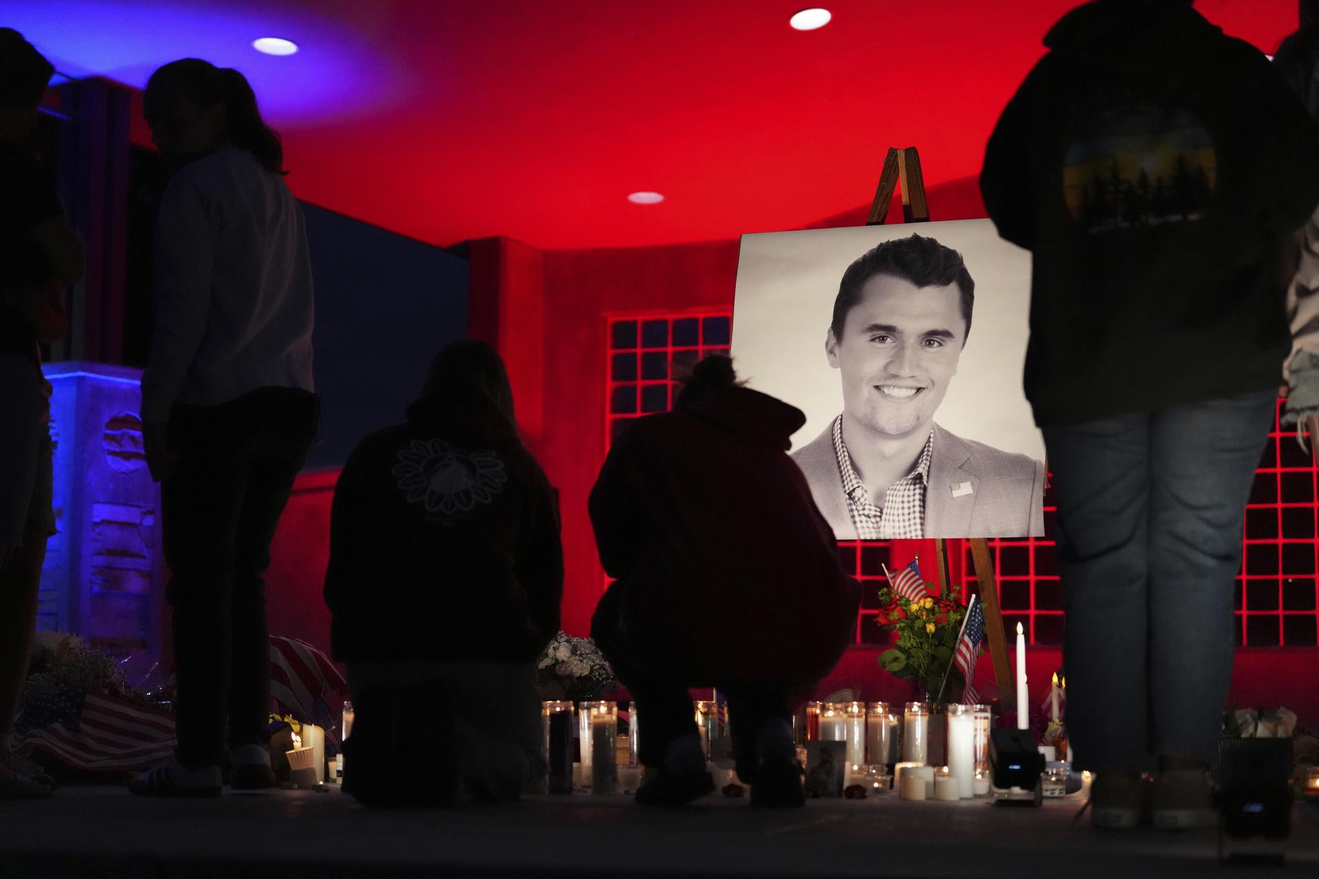 People place lit candles below a photo of Charlie Kirk, the CEO and co-founder of Turning Point USA who was shot and killed, at a vigil in his memory on Thursday in Orem, Utah. (AP Photo/Lindsey Wasson).