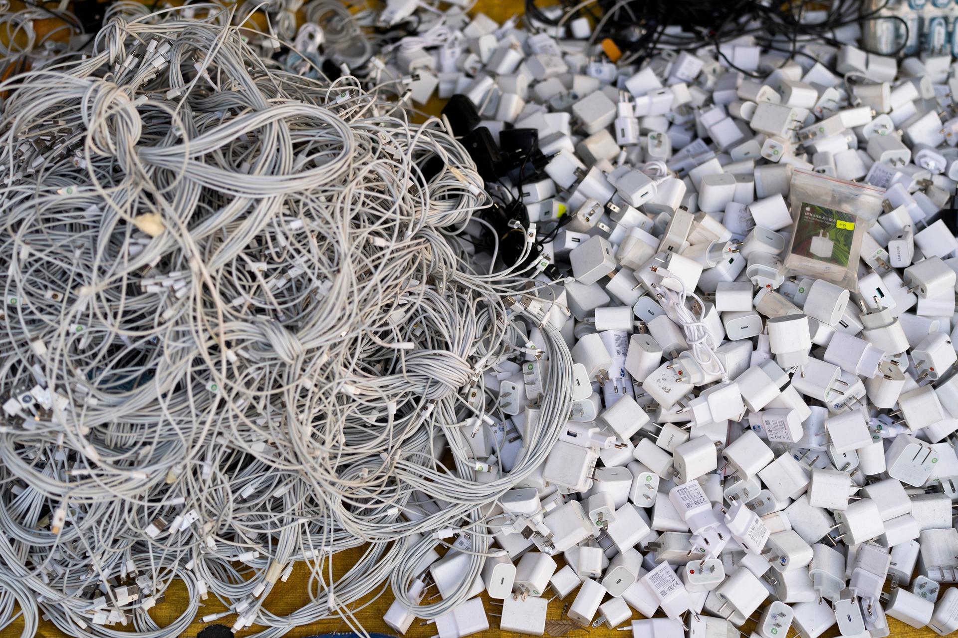 Used charging cables and power adapters are piled up at a shop in Nhat Tao market, the largest informal recycling market in Ho Chi Minh City, Vietnam, 2024.