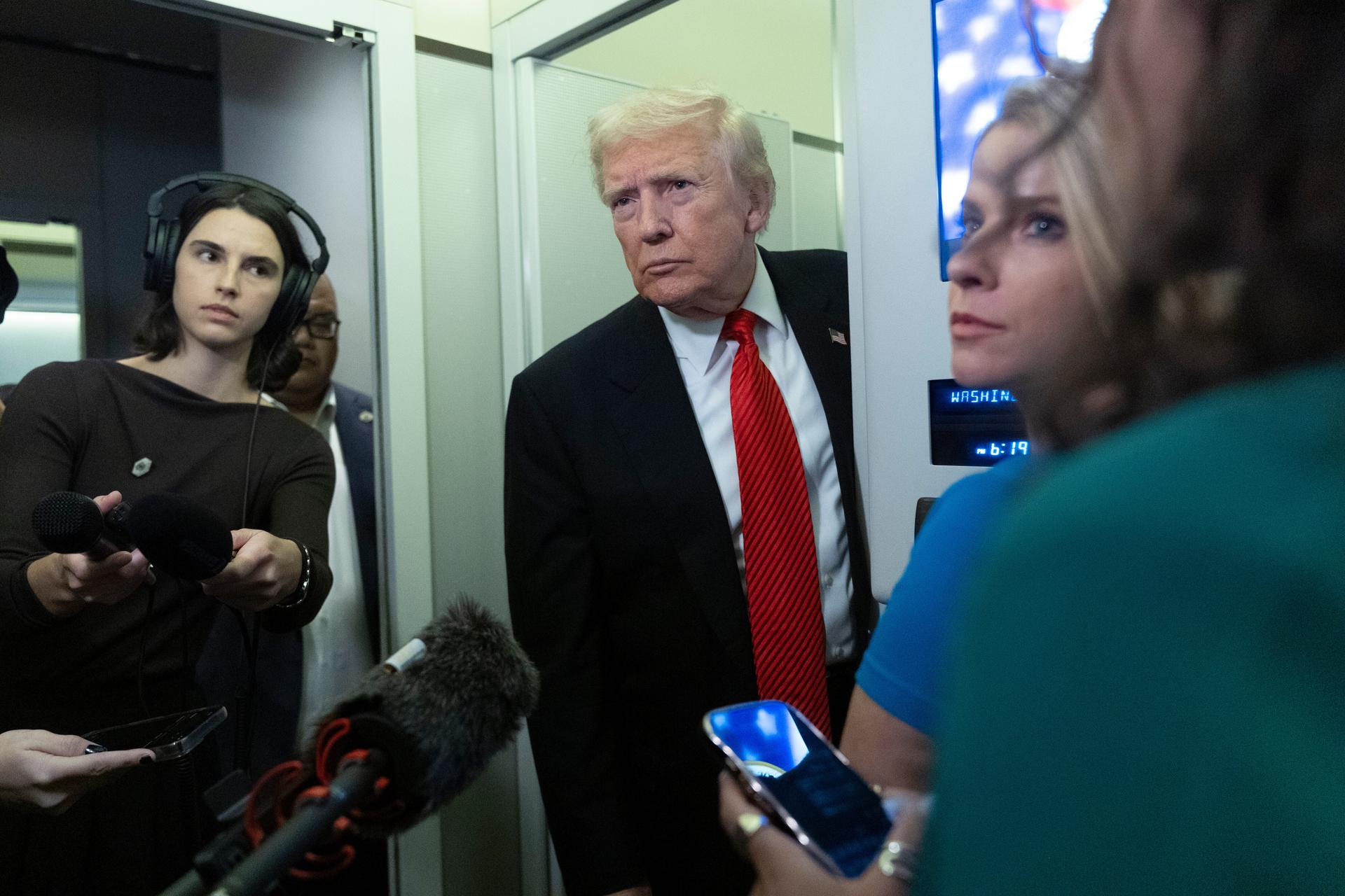 President Donald Trump speaks to reporters on board Air Force One on his way back to the White House from a weekend trip at his Mar-a-Lago estate in Palm Beach, Fla., Sunday. 