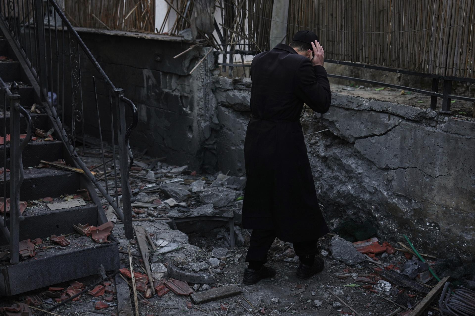 A man inspects a damaged house struck by a rocket fired from Lebanon, in Hatzor HaGlilit, northern Israel, Wednesday.