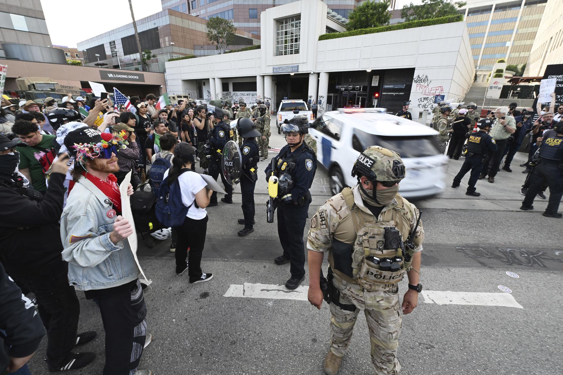 Law enforcement stand guard as vehicles enter the Federal Building during a protest in June 13 in Los Angeles. (AP Photo/Wally Skalij)