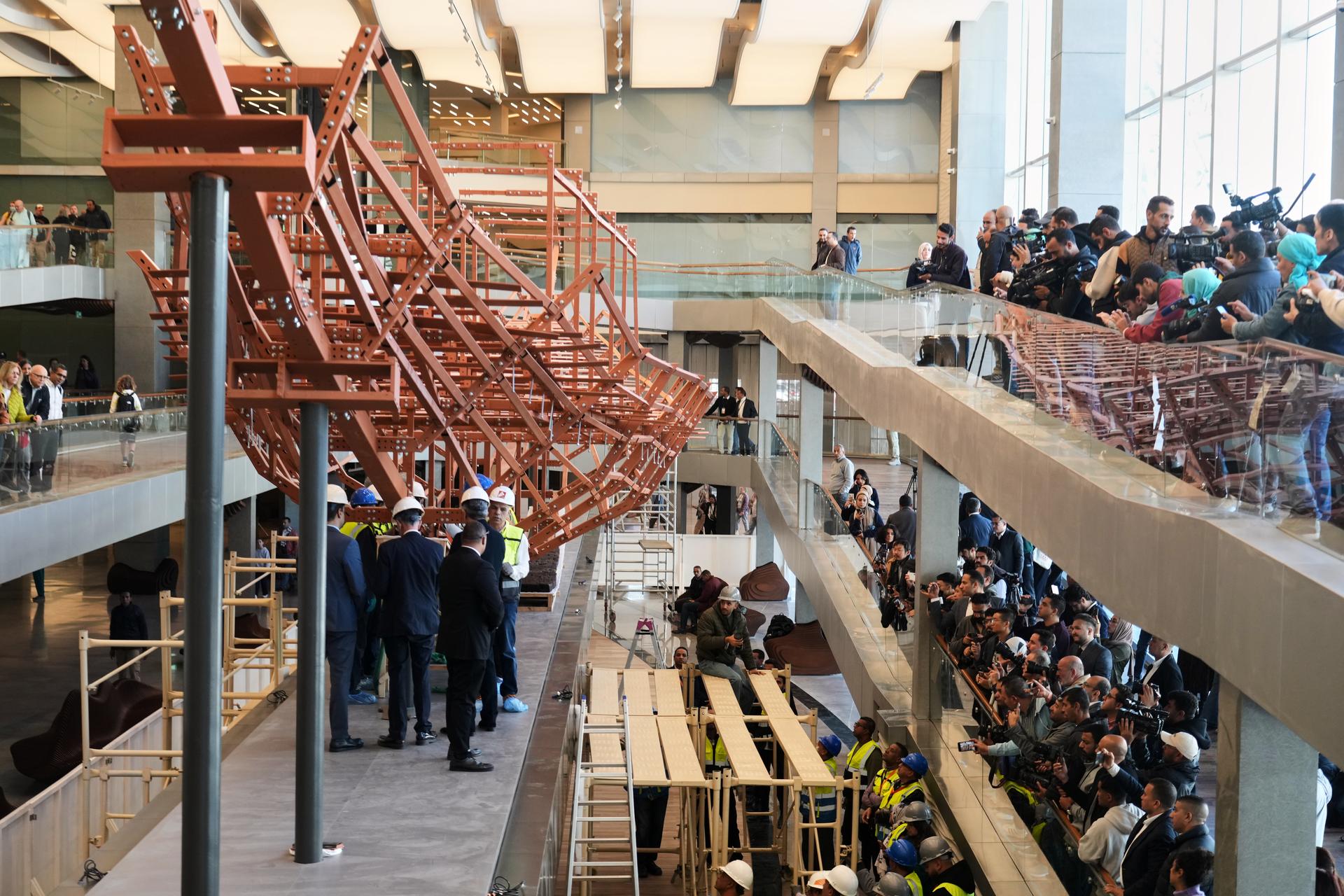 People film archeologists as they reassemble the second solar boat of King Khufu, at the Grand Egyptian Museum in Giza, Egypt, Dec. 23, 2025.