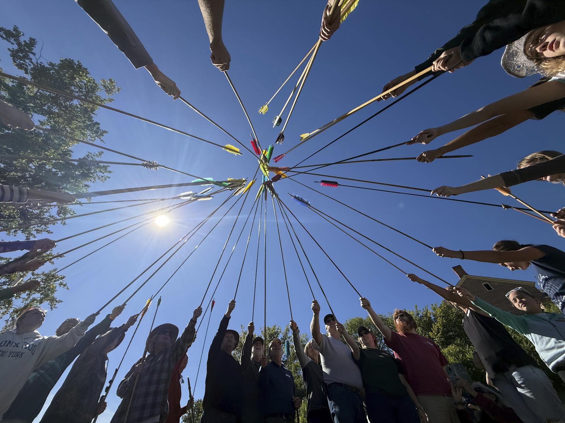 Competitors raise their darts as part of the opening ceremony for the Northeastern Atlatl Championship in Addison, Vt.