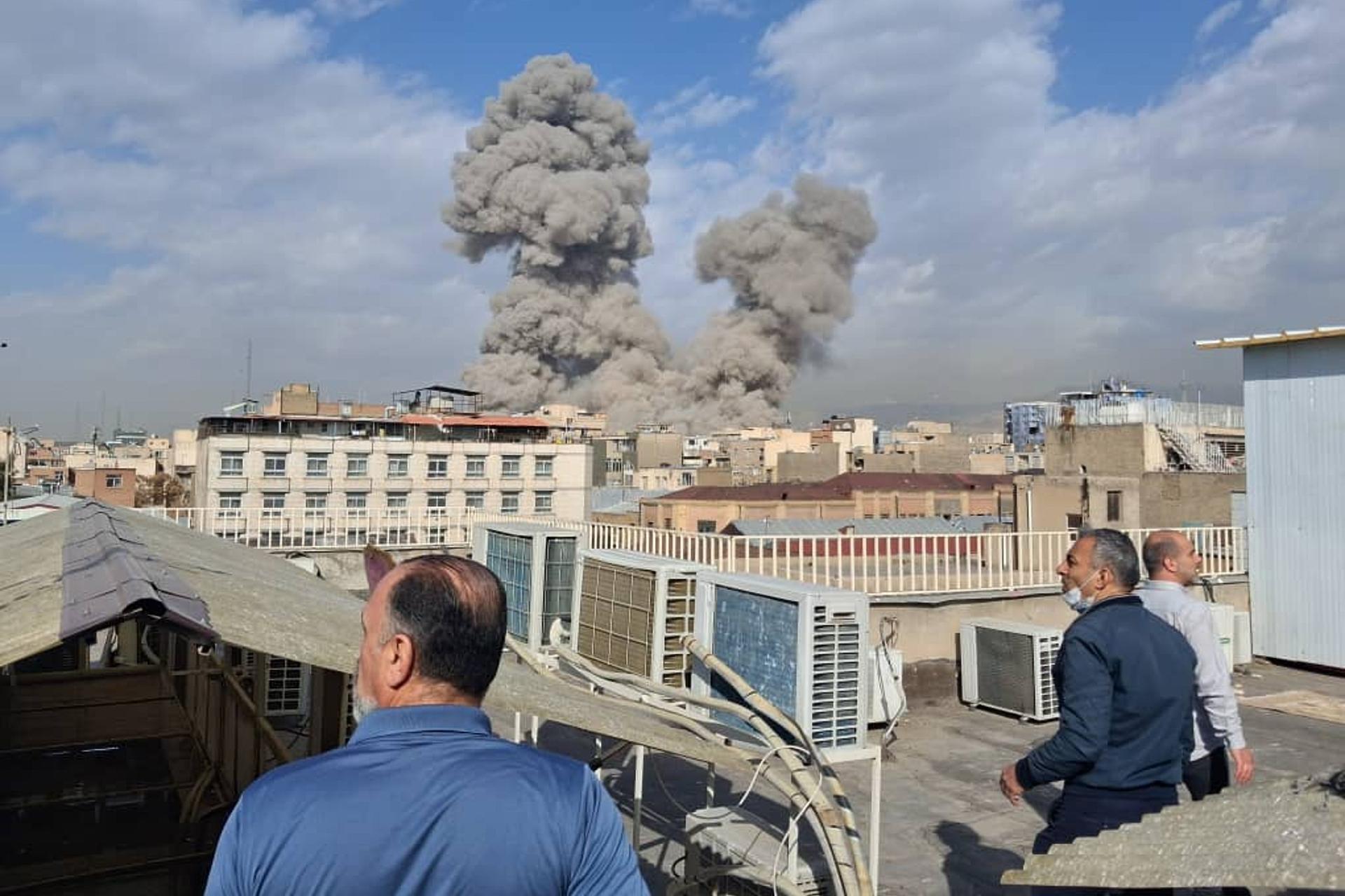 People watch as smoke rises on the skyline after an explosion in Tehran, Iran, Saturday.