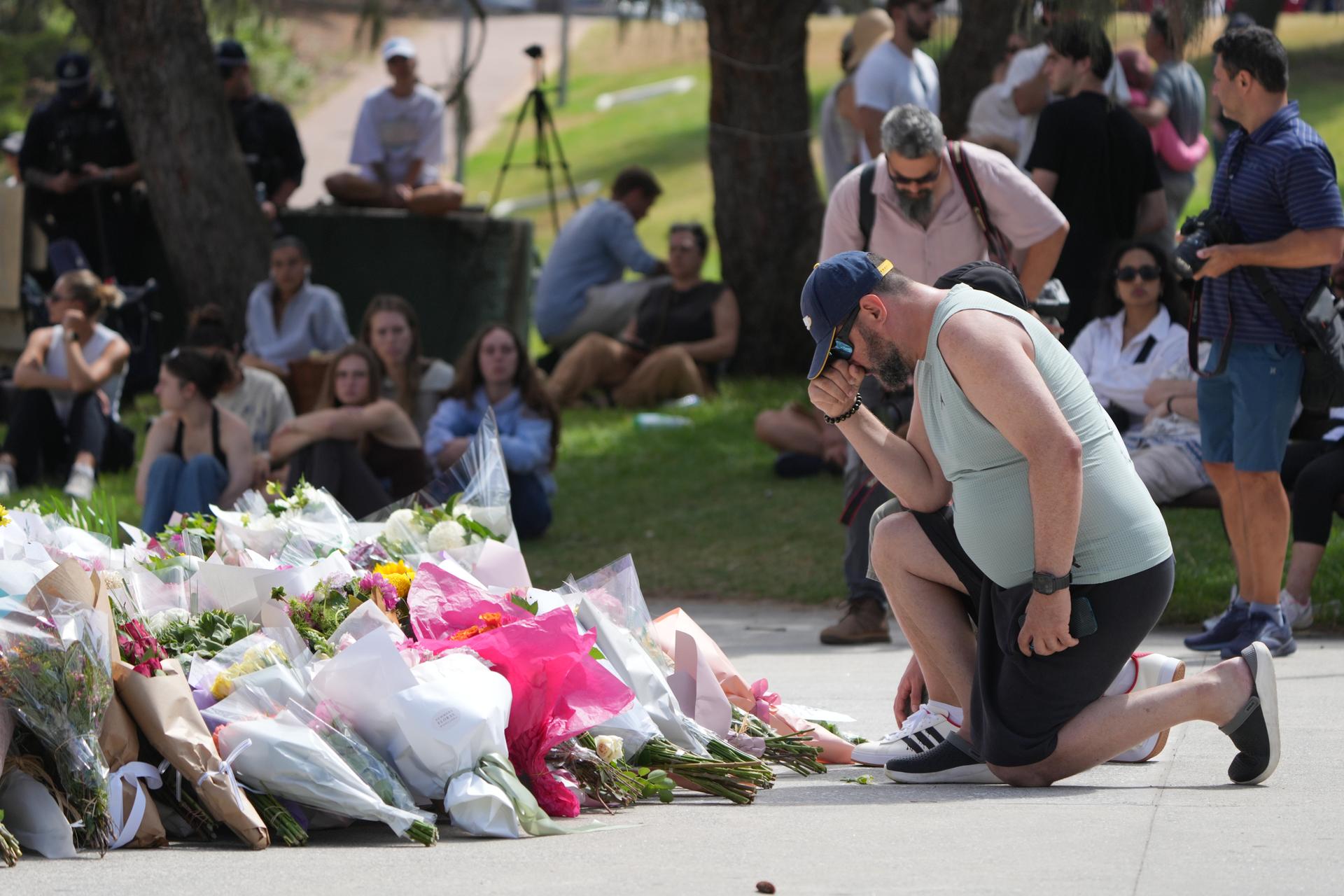 A man kneels after laying flowers at a memorial outside the Bondi Pavilion at Sydney's Bondi Beach, Monday.