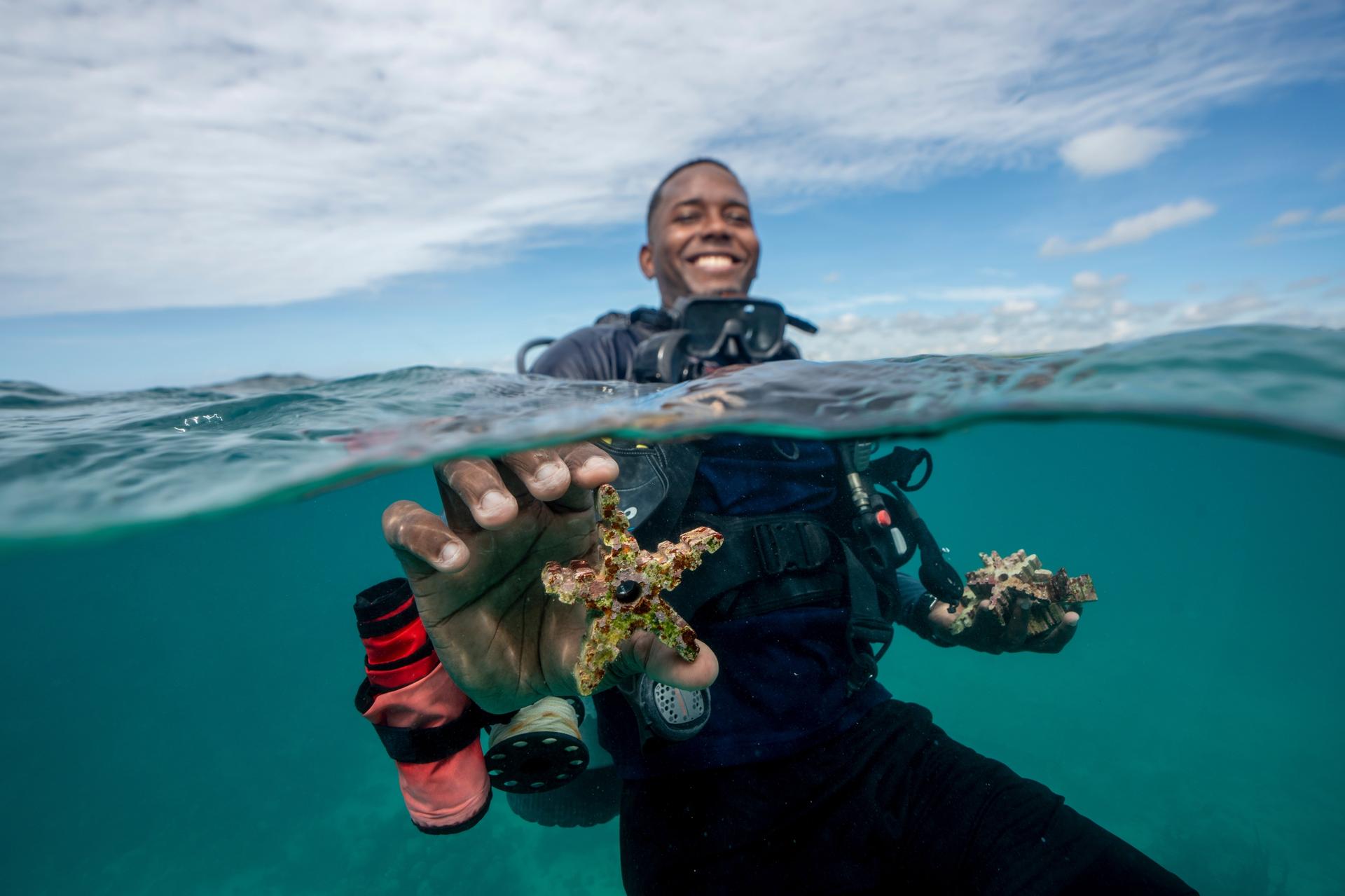 Michael del Rosario shows a piece of ceramic with corals growing on it in Bayahibe, Dominican Republic, in October. (AP Photo/Francesco Spotorno)
