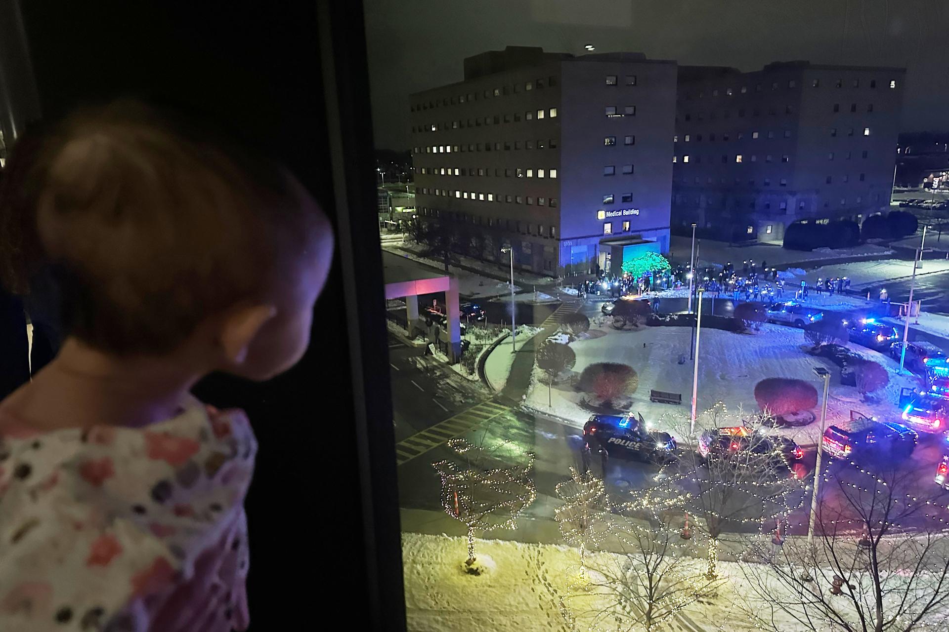 A child looks out the window at volunteers who are shining lights up into the pediatric wing of Corewell Health Children's on Dec. 10. (AP Photo/Mike Householder)