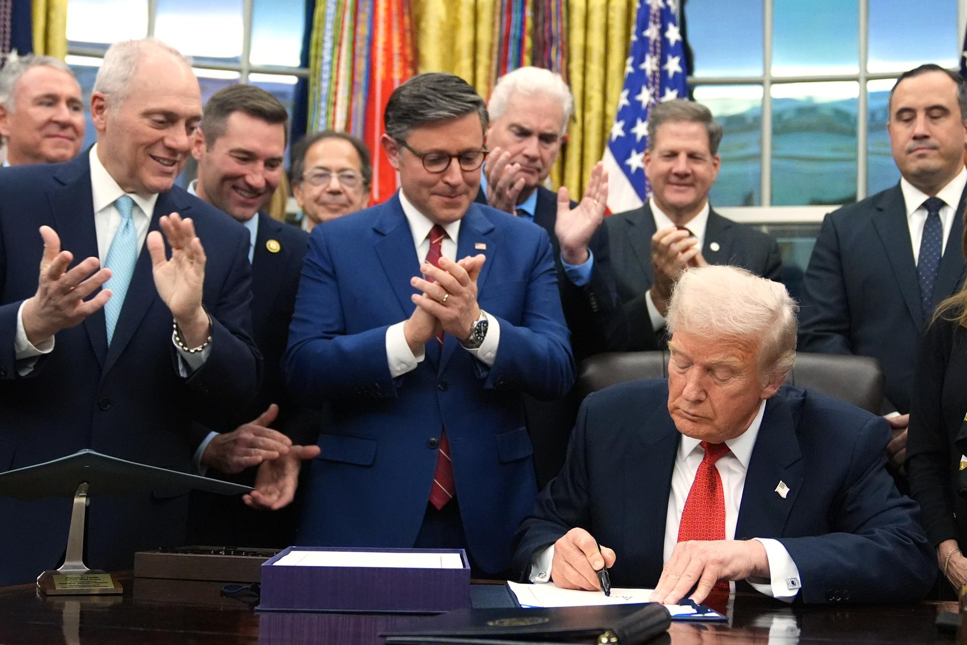 As Rep. Steve Scalise, R-La., left, and House Speaker Mike Johnson of La., applaud, President Donald Trump signs the funding bill to reopen the government, in the Oval Office of the White House, Wednesday, in Washington.