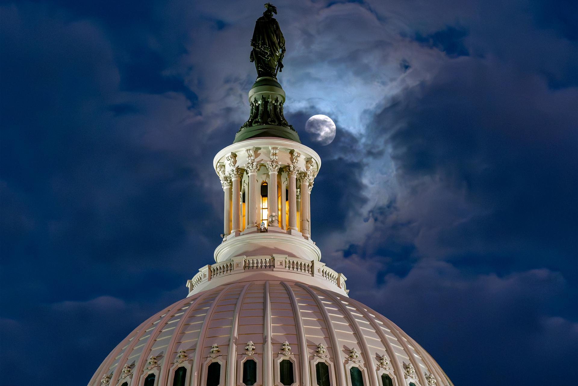 The moon emerges from the clouds over the U.S. Capitol dome in Washington, 2025.