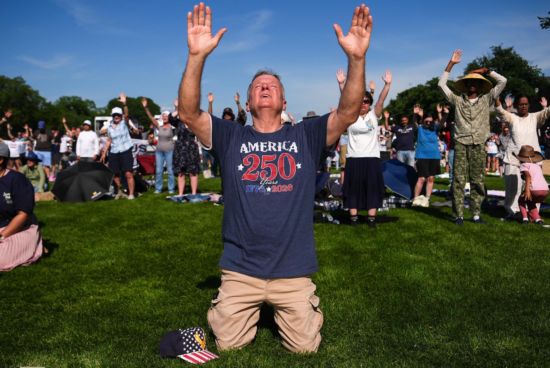 Teddy May, from Mobile, Ala., kneels while worshiping during Rededicate 250, on the National Mall Sunday in Washington.