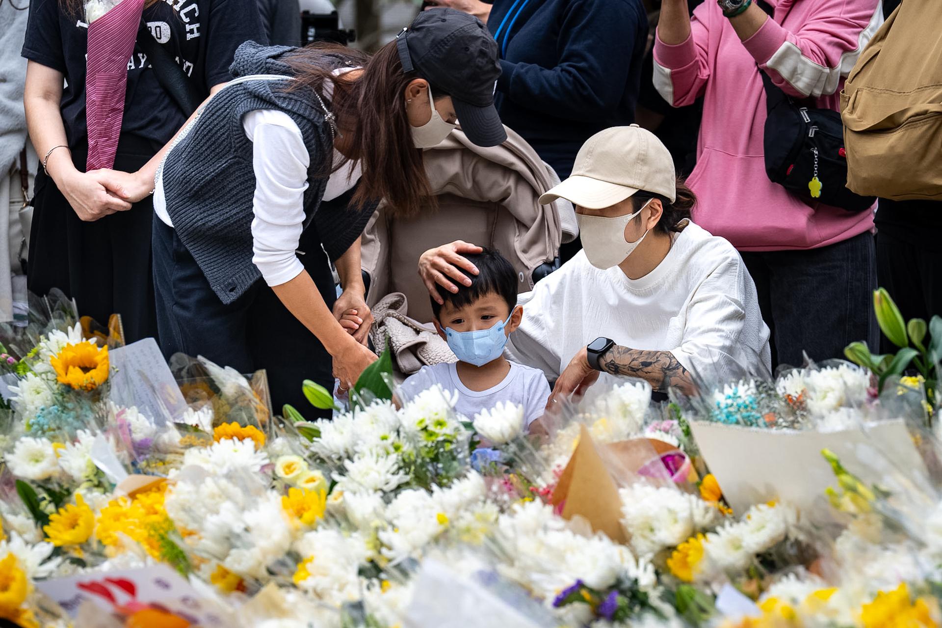 A child looks at the flowers for the victims near the site of a deadly Wednesday fire at Wang Fuk Court on Sunday. (AP Photo/Chan Long Hei)