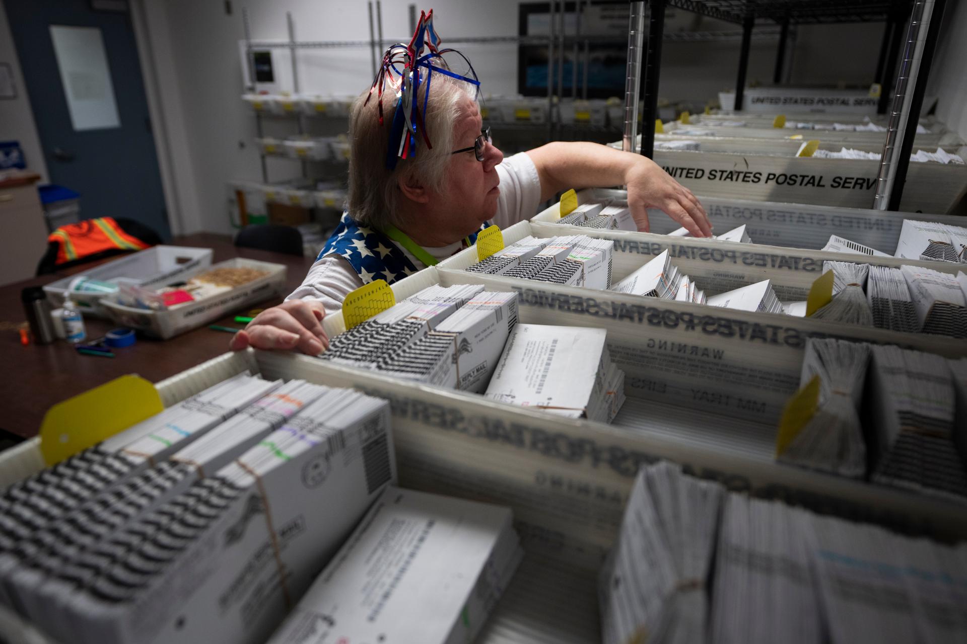 Election worker Wendy Wimer looks through vote-by-mail ballots for the presidential primary election at the Clark County Elections Office in Vancouver, Wash., in 2024. 