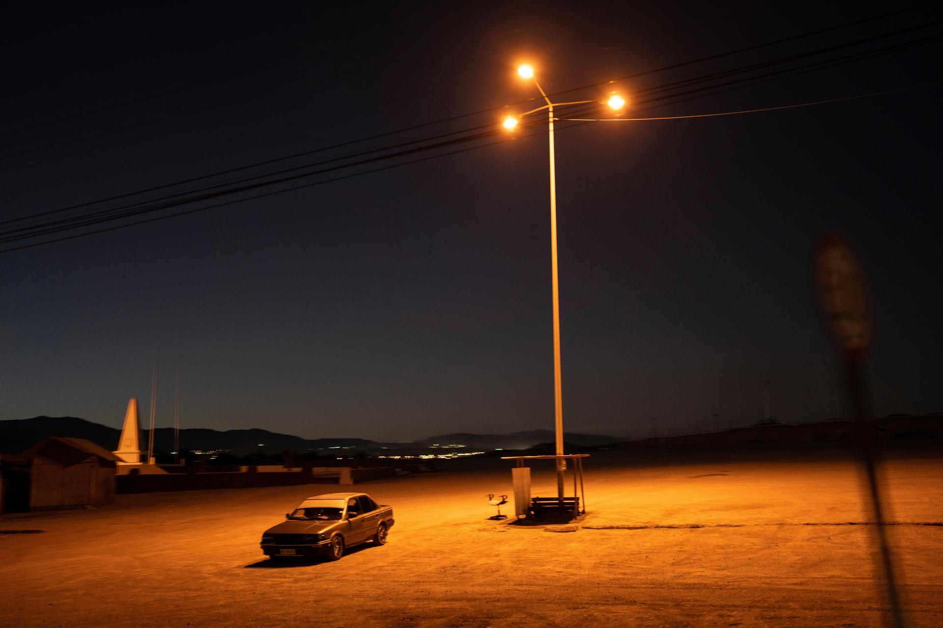 A driver sits in his car in an empty parking lot in Calama, Chile, 2023.