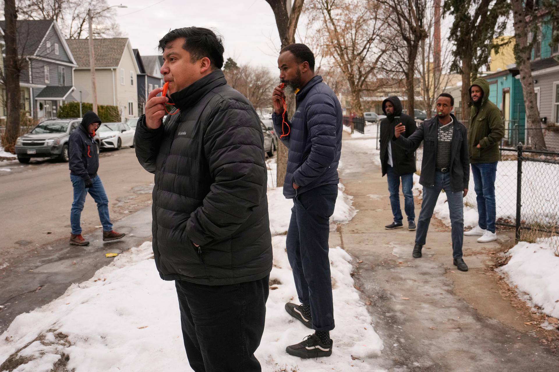 Minneapolis City Council Member Jason Chavez, second from left, blows a whistle with other activists to warn people of federal immigration officers on Thursday. (AP Photo/John Locher)