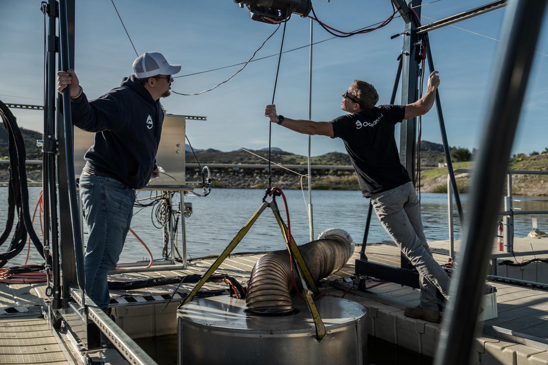 Two OceanWell engineers lower a prototype reverse osmosis pod into a California reservoir in December. (AP Photo/Annika Hammerschlag)