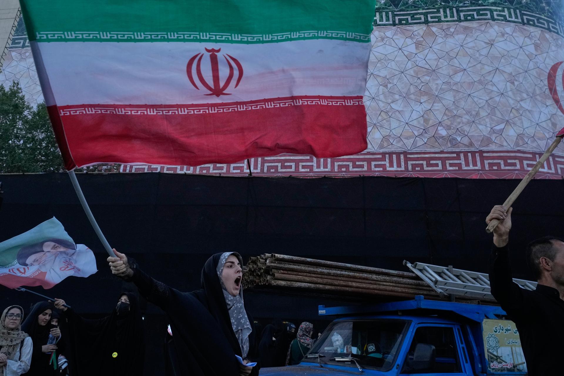 A woman waves an Iranian flag at the Islamic Revolution square in Tehran, Iran, Sunday. 