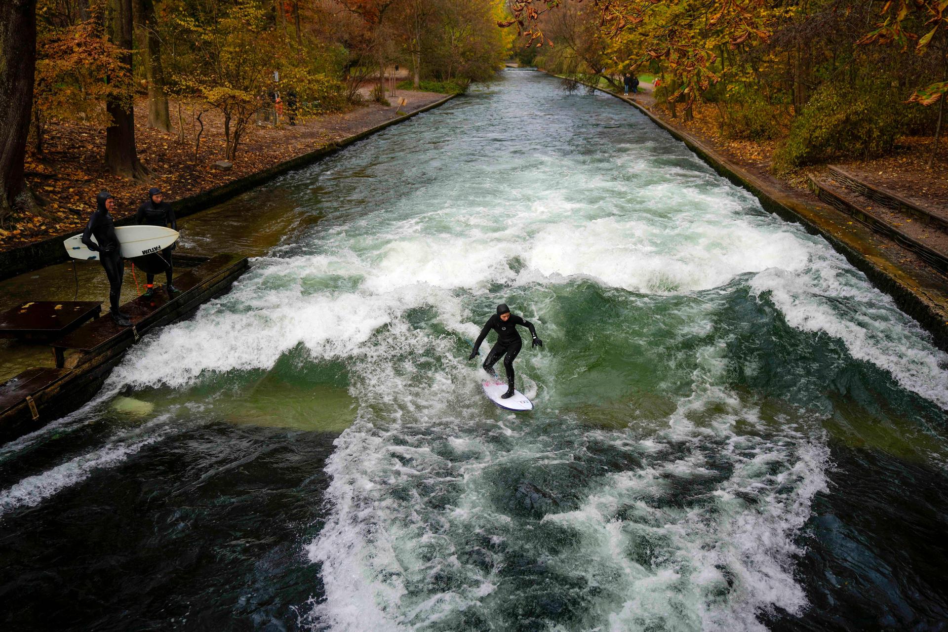 A surfer rides on an artificial wave in the river 'Eisbach' downtown in Munich in 2024. (AP Photo/Matthias Schrader)