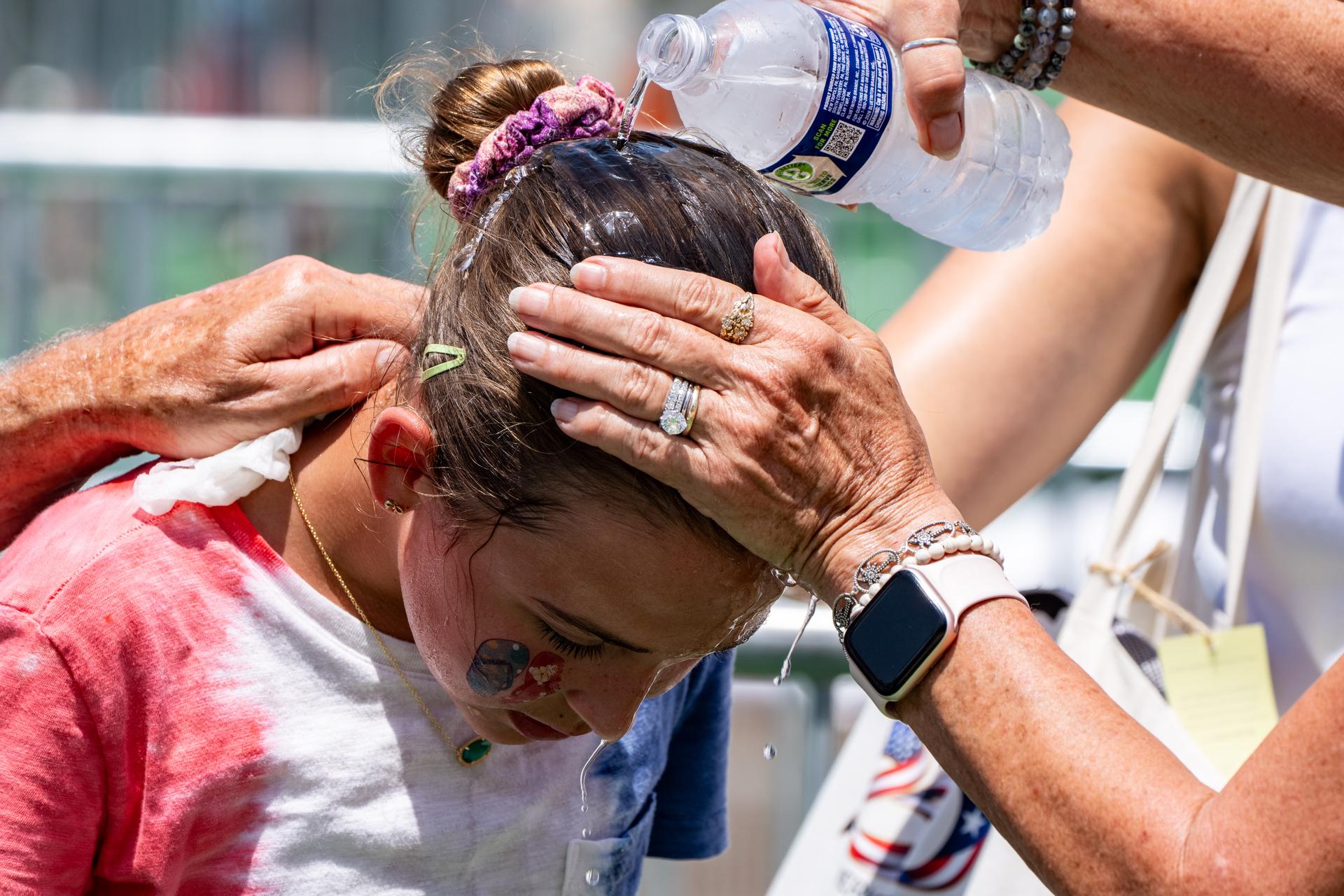 Ruth, 11, gets cold water poured on her head to cool off at the Great American State Fair on the National Mall, Thursday, in Washington. 