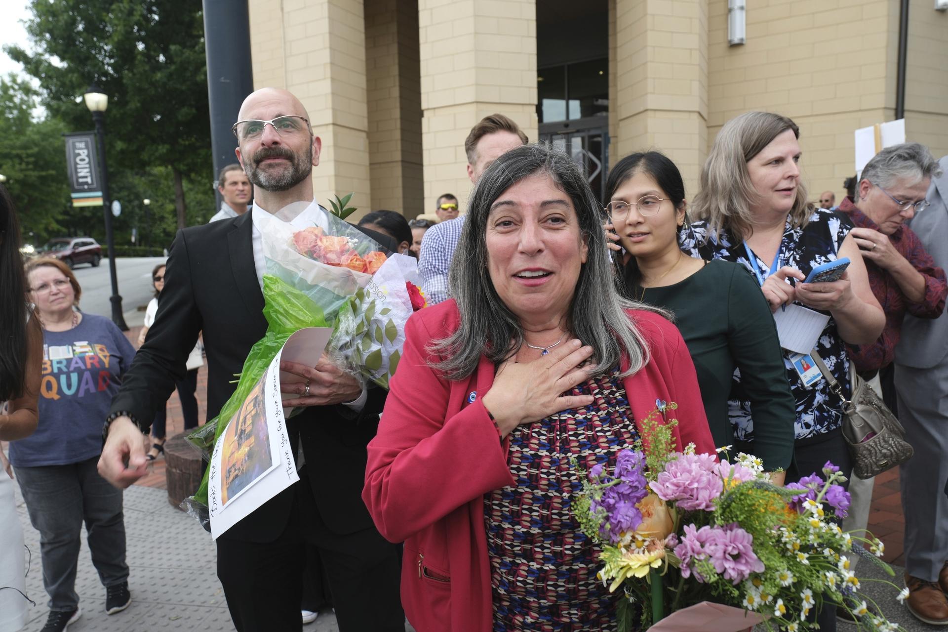 Dr. Demetre Daskalakis, left, and Dr. Debra Houry are greeted by supporters at a rally for the departing scientific leaders at the Centers for Disease Control and Prevention outside the CDC headquarters, Thursday, in Atlanta. 