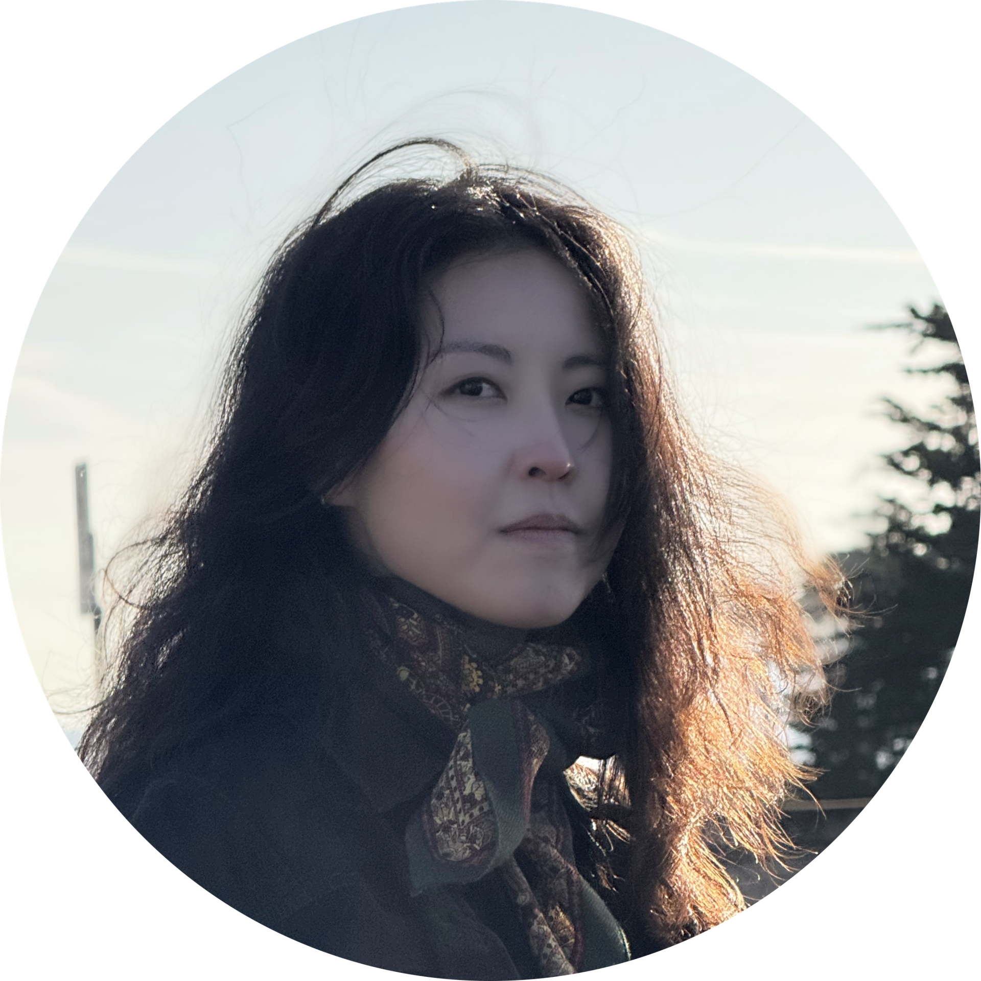 Hannah, an Asian woman with long dark hair, wears a neutral expression and a patterned scarf with a dark jacket.