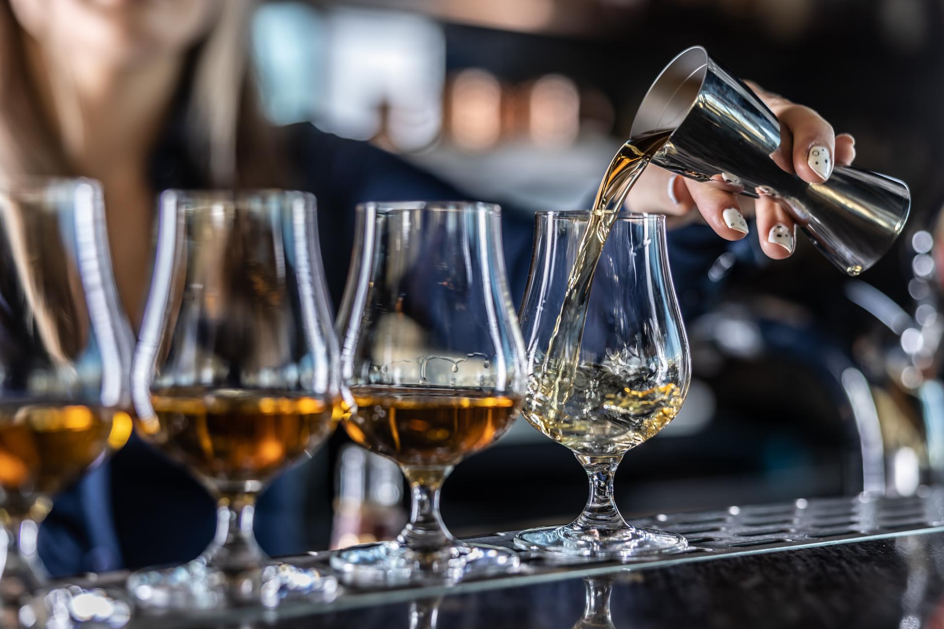 A bartender pours drinks into glasses