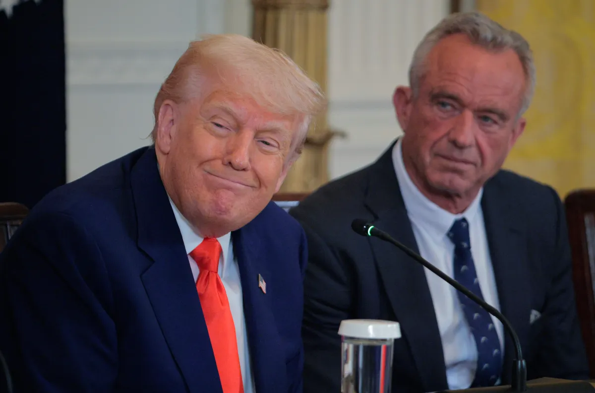 President Donald Trump smiles with US Health secretary Robert F. Kennedy Jr. behind him.