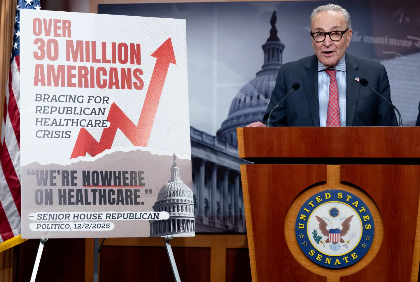Sen. Chuck Schumer stands next to a billboard on the rising number of uninsured