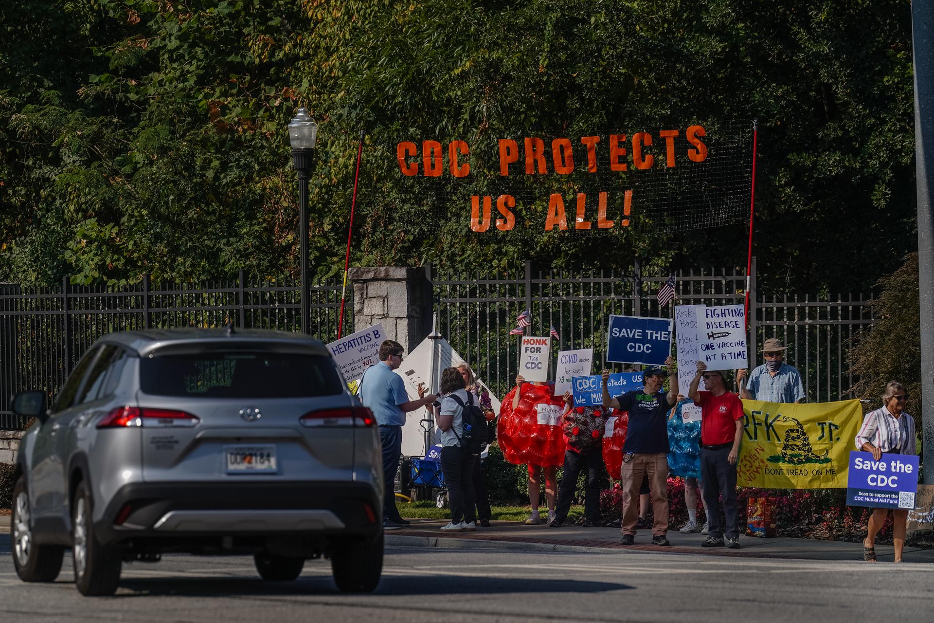 CDC supporters rally outside its headquarters, with a sign saying 