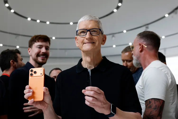 a man in a black zip up short sleeve turtleneck with short white hair holding up an orange iPhone with other men behind him (including Mr.Beast)