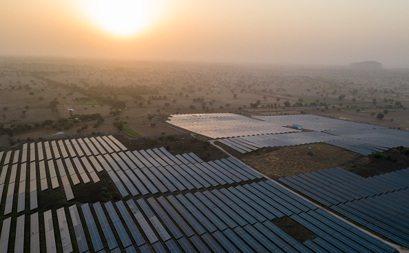 Large arrays of solar panels seen on scrubland.