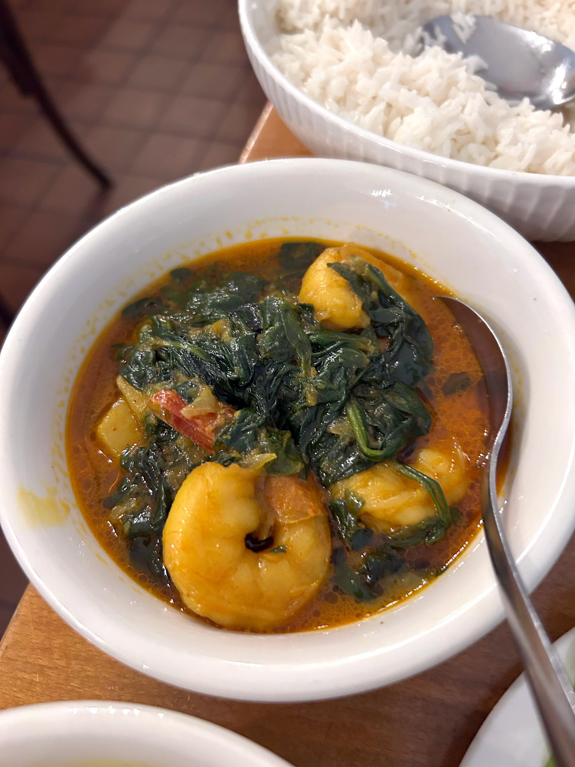 A broth with shrimp and cooked spinach.