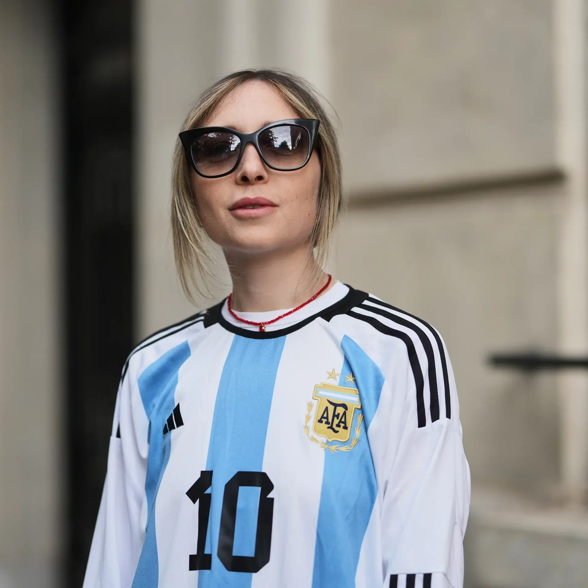 Woman wearing soccer jersey and sunglasses.