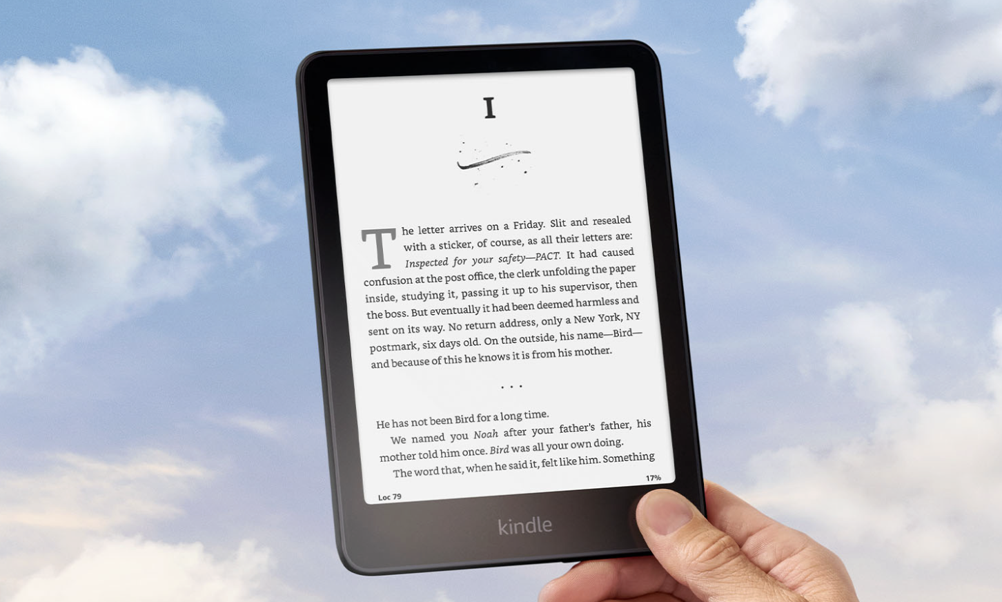 A hand holding a black Kindle reader.