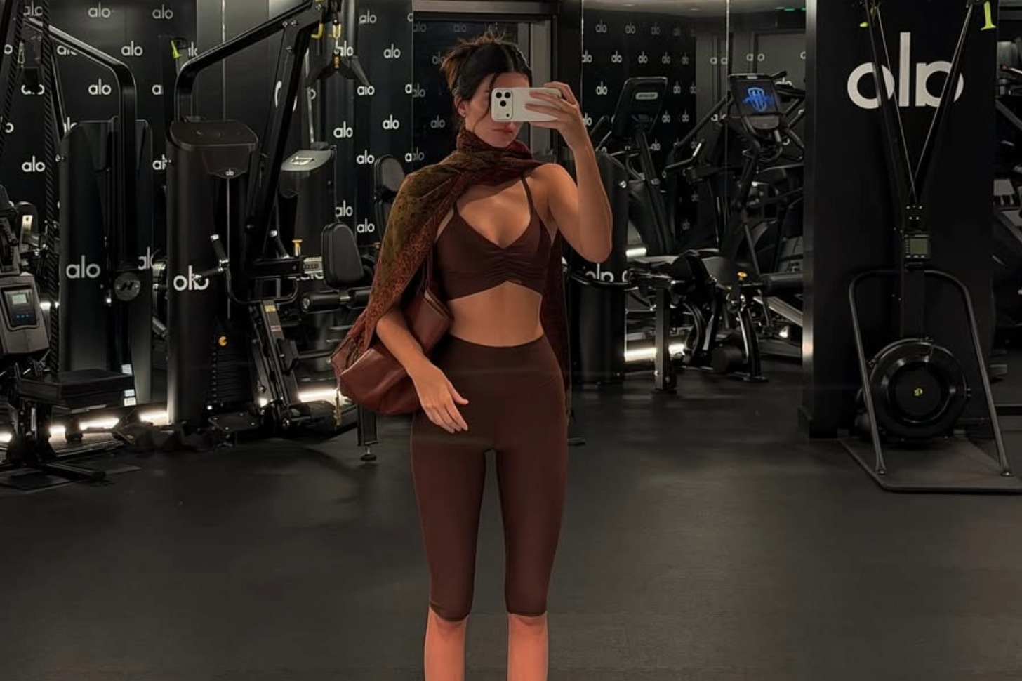 Kendall Jenner posing in a mirror with a brown matching workout set.