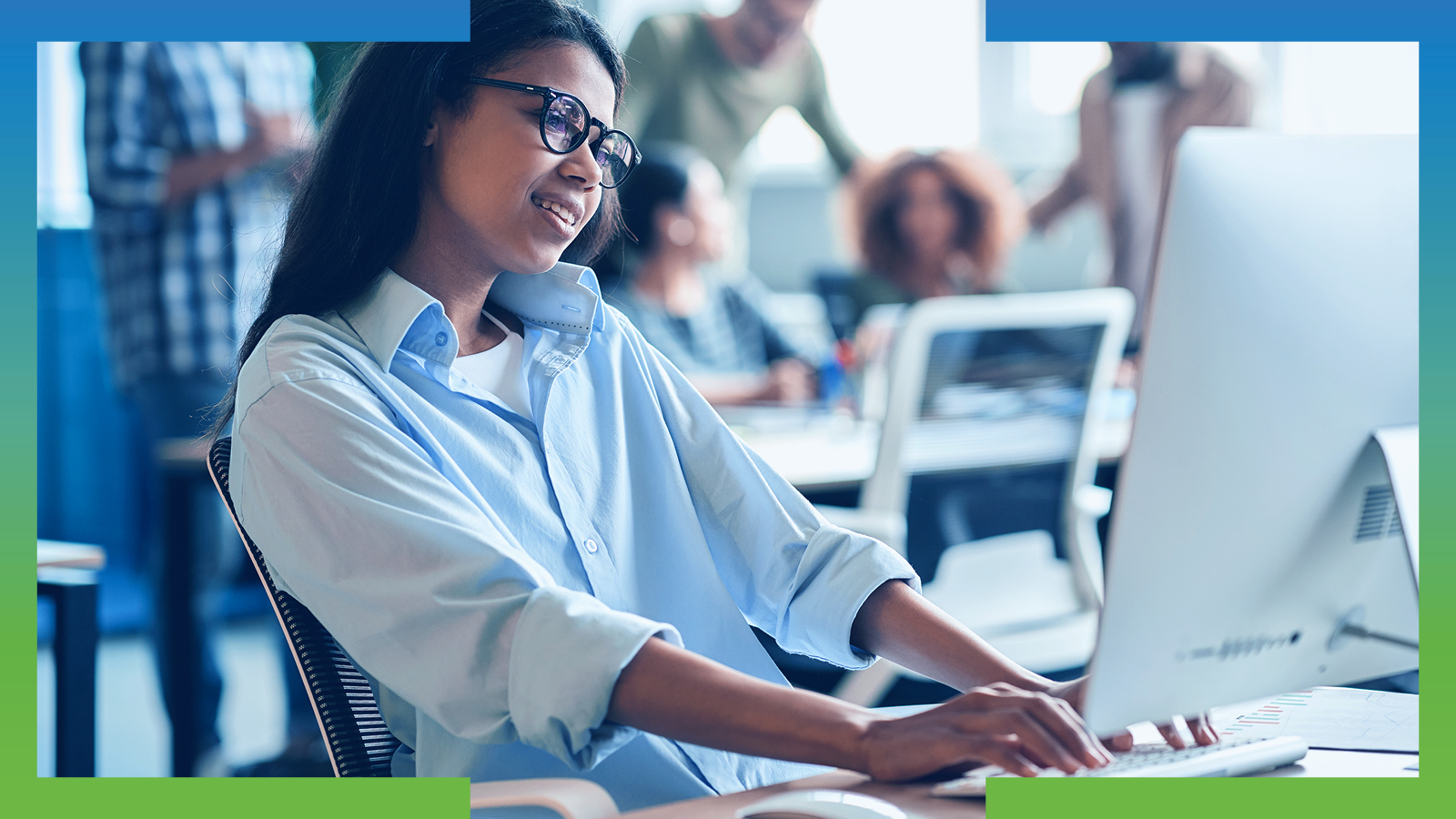 Woman smiling while working at a desktop computer in a busy office, framed by blue and green design accents.