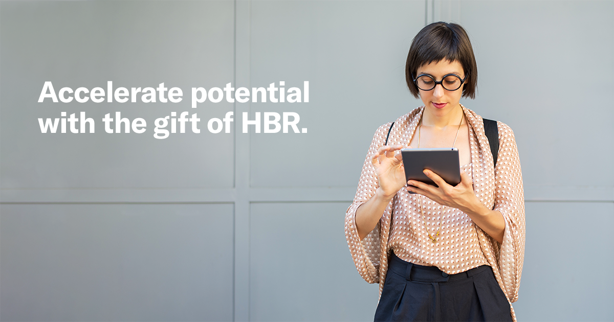 A person with glasses uses a tablet against a gray background. The text reads, 'Accelerate potential with the gift of HBR, conveying a professional tone.
