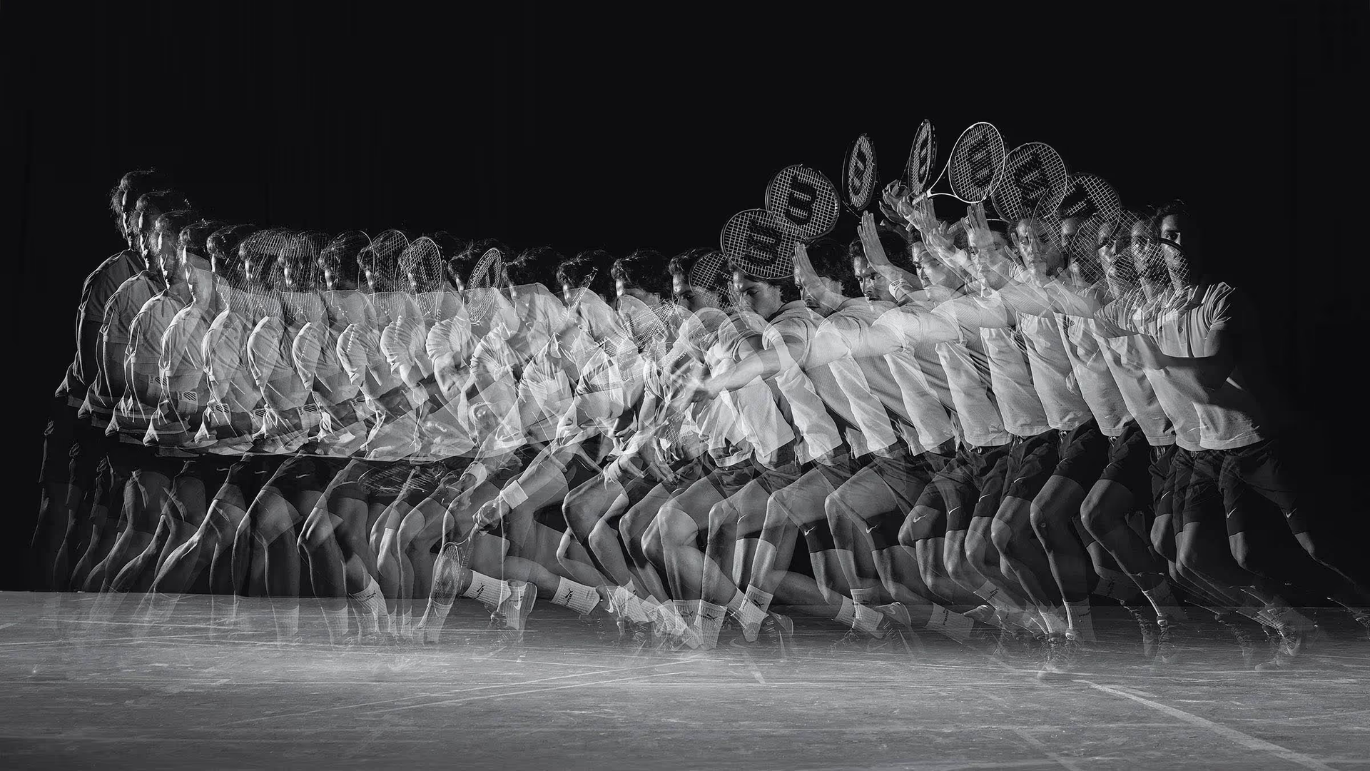 Black-and-white long-exposure image showing a tennis player moving through multiple positions during a swing.