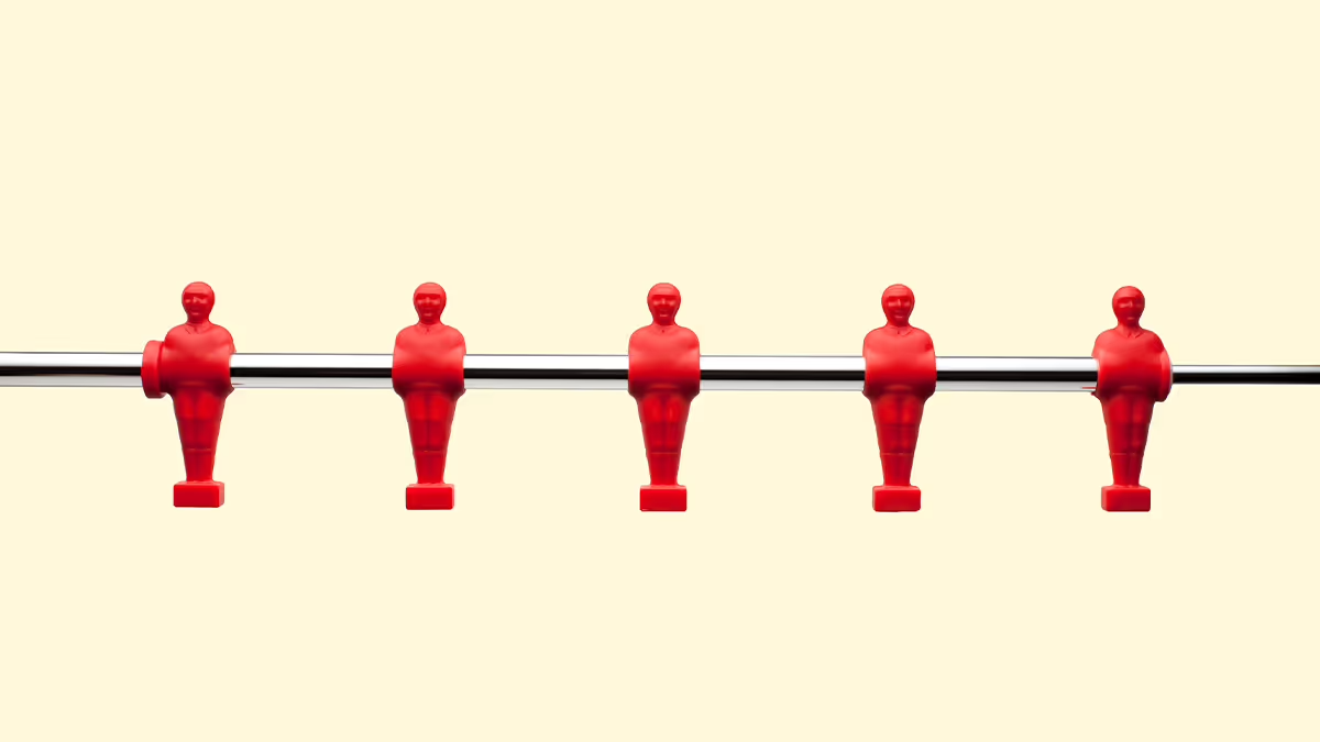 Five red foosball figures evenly spaced on a horizontal metal rod against a light beige background.