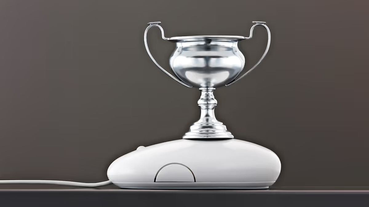 A picture of a trophy on top of a computer mouse.