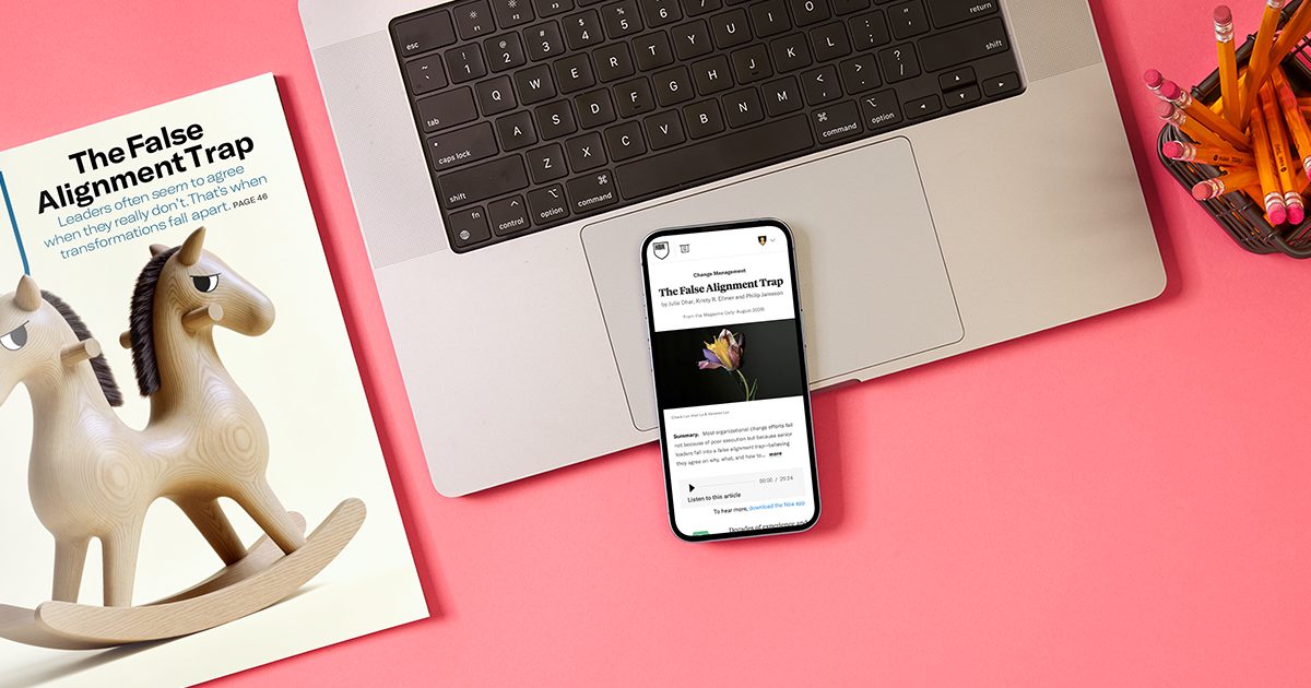 Magazine, laptop, and smartphone featuring The False Alignment Trap article on a pink desk.