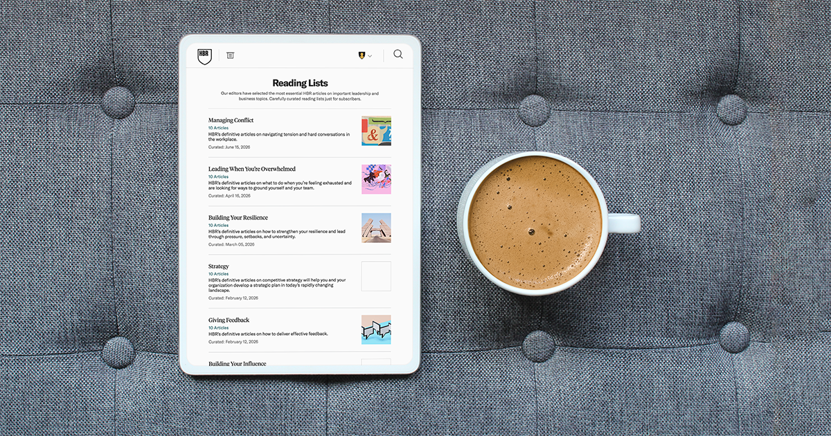 HBR Reading Lists displayed on a tablet beside a cup of coffee on a gray upholstered surface.