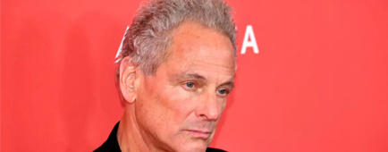 Lindsey Buckingham looking down and to the side in a black blazer over a black shirt Lindsey Buckingham looking down and to the side in a black blazer over a black shirt