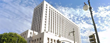 A view of multistory white buildings against a cloudy light blue sky